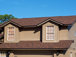 Asphalt shingles being expertly installed on a Bonney Lake home under a clear spring sky.