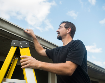 Homeowner inspecting roof shingles for damage in Puyallup